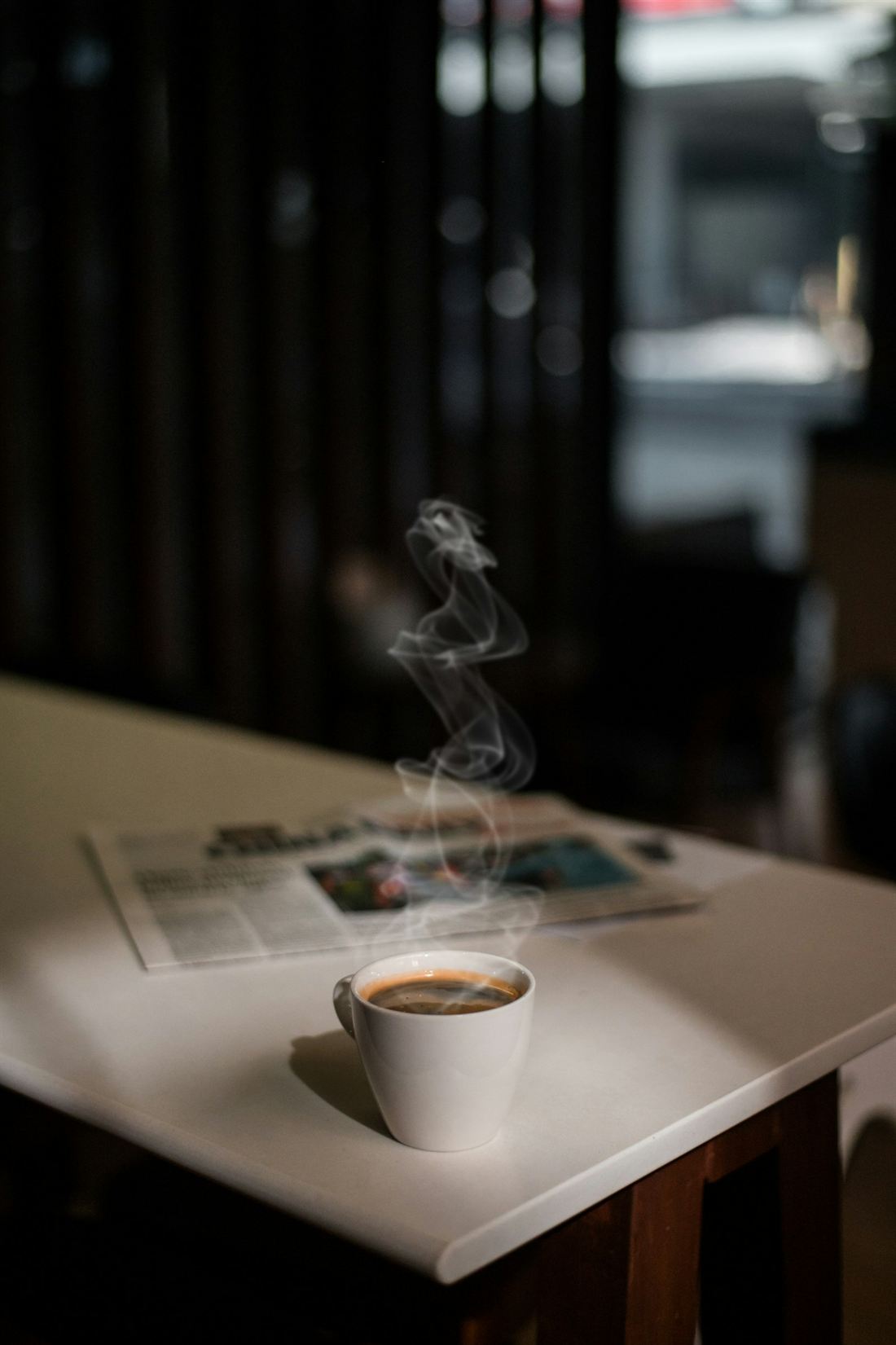 Un café fumant posé sur une table sombre