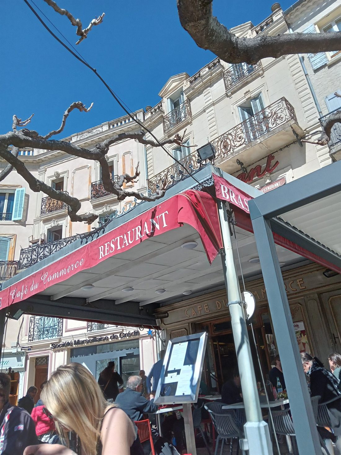 Façade et terrasse du Café du Commerce sous son auvent rouge